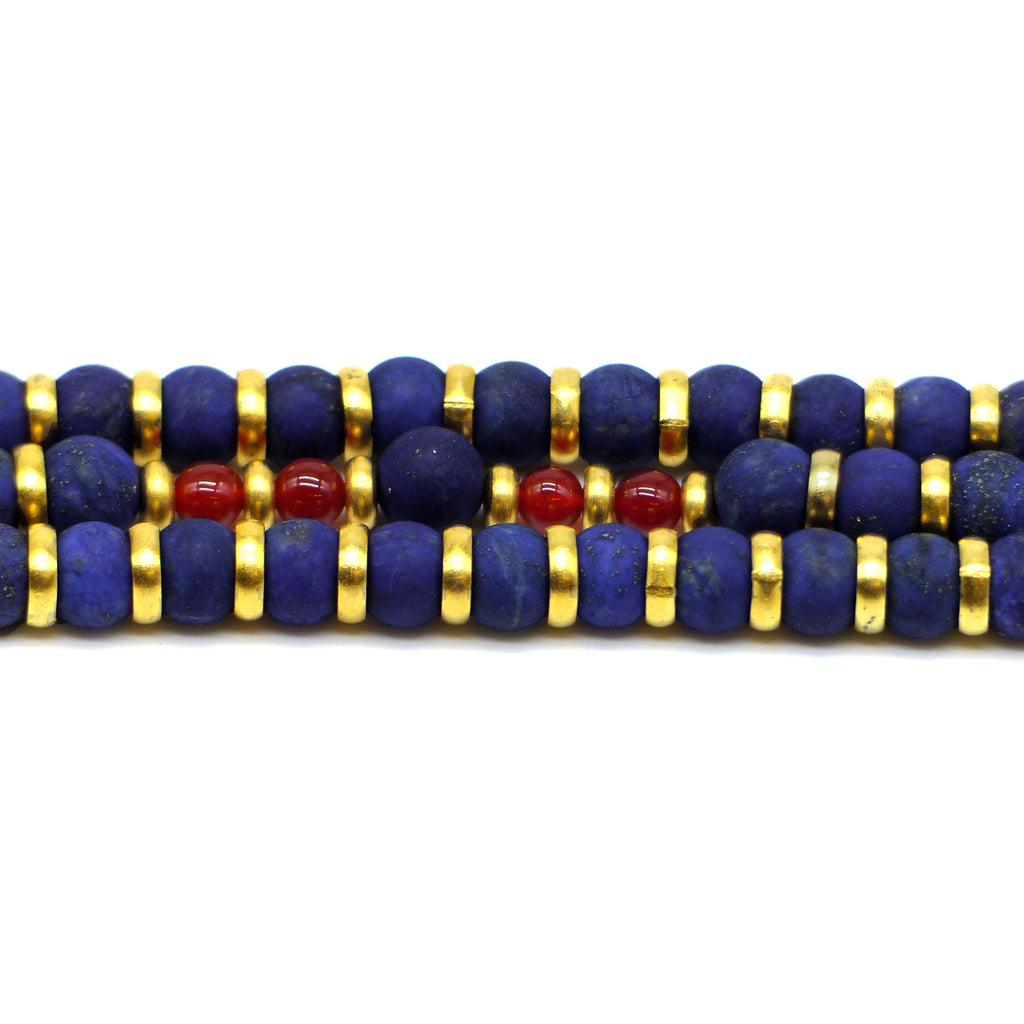Detail of a triple strand lapis bead necklace with gold colored and carnelian accents. Shown on  a white background.
