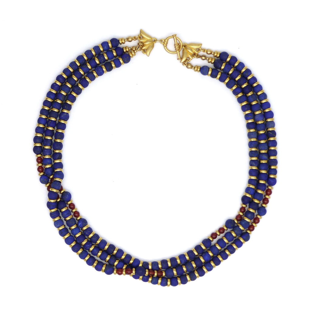 Triple strand lapis bead necklace with gold colored and carnelian accents. Shown with clasp closed on a white background.