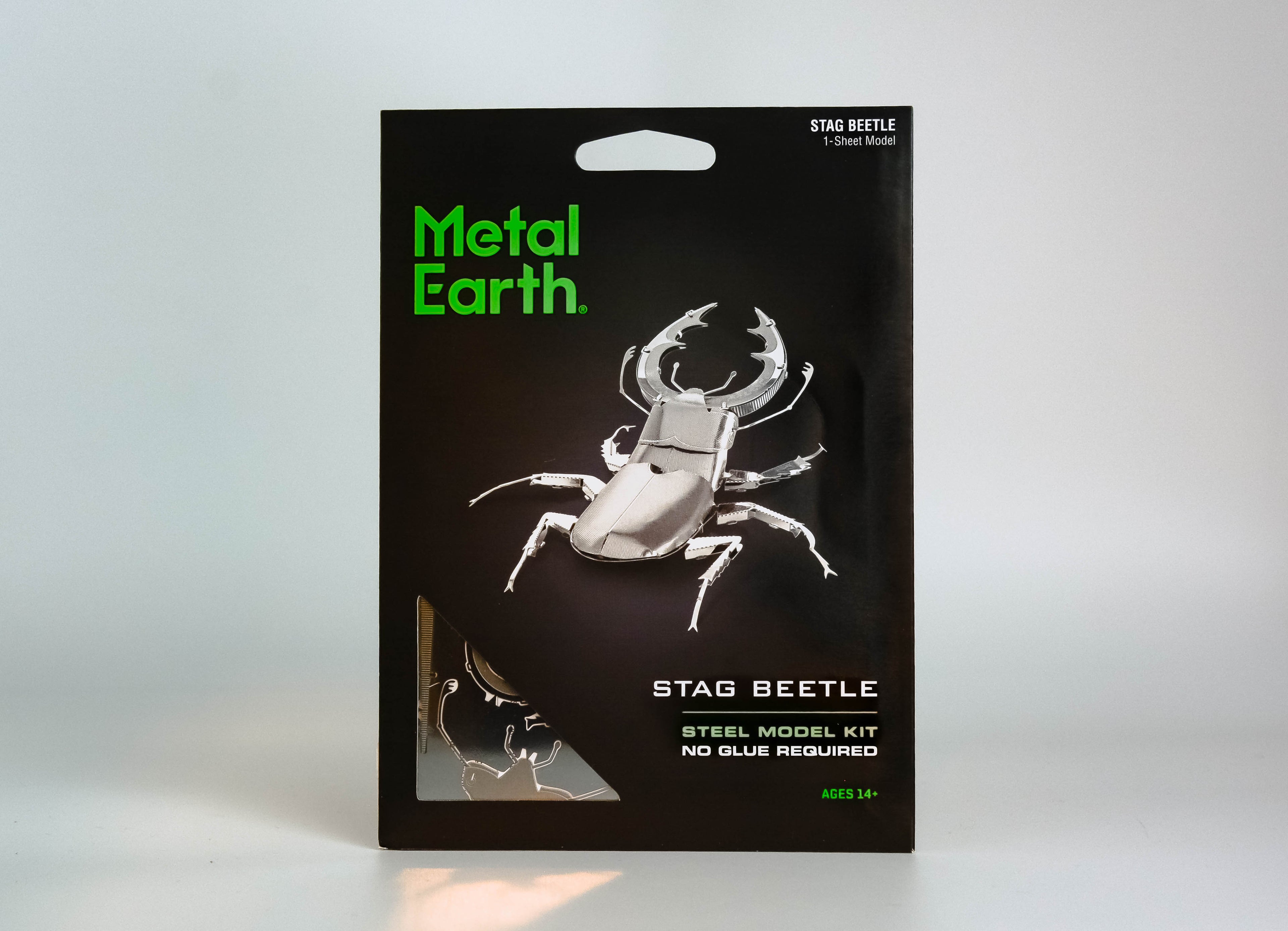 Black activity kit with green text "metal earth," silver stag beetle in center. On white background. 