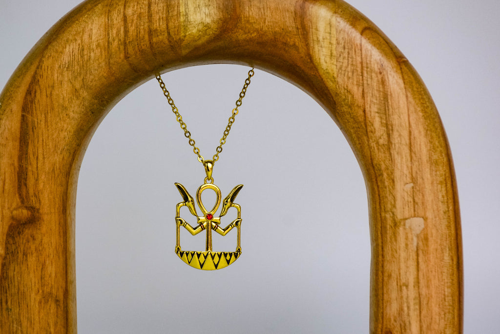 Ankh necklace on wooden arch, off-white background. 