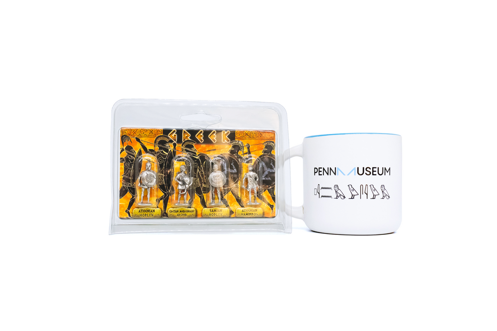 Penn Museum mug to the right of four silver Greek warrior figurines in plastic container. On white background. 