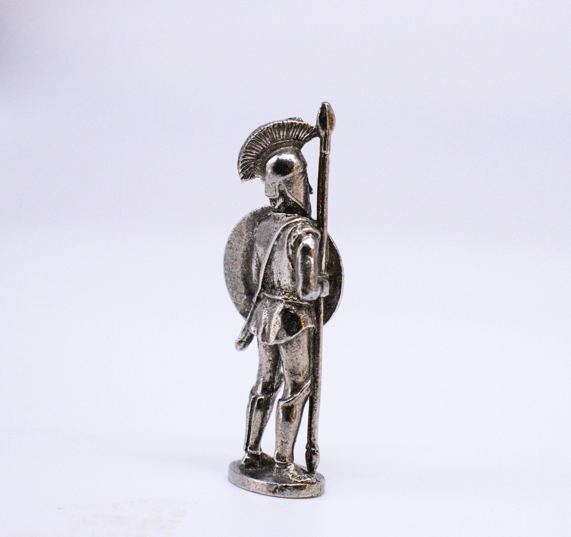 Silver-colored Samian Hoplite back view of figurine. Samian Hoplite wearing helmet, holding spear, carrying shield. On white background. 