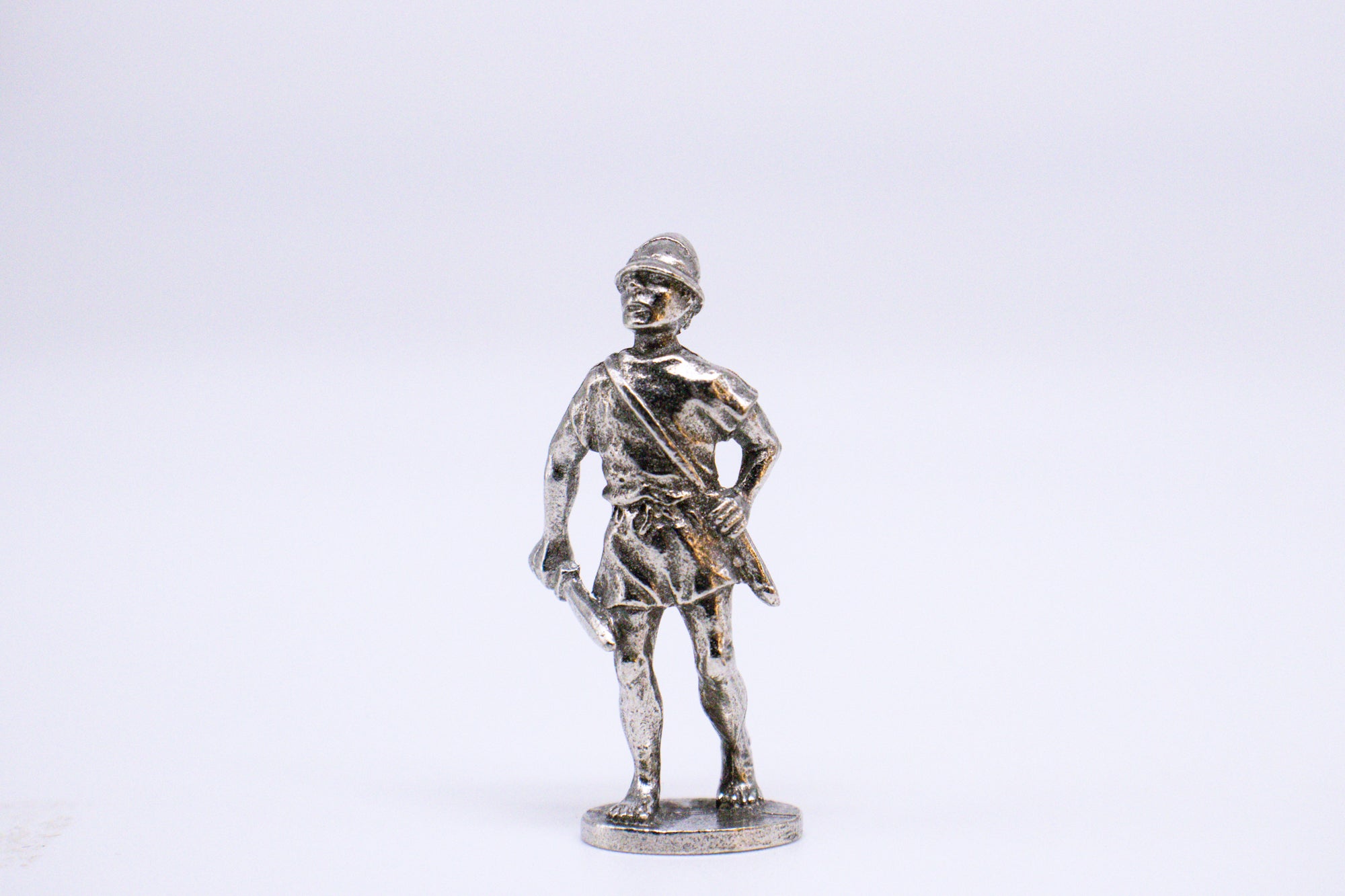 Silver-colored Athenian Hamippos wearing hat, holding sword and messenger style bag. On white background. 