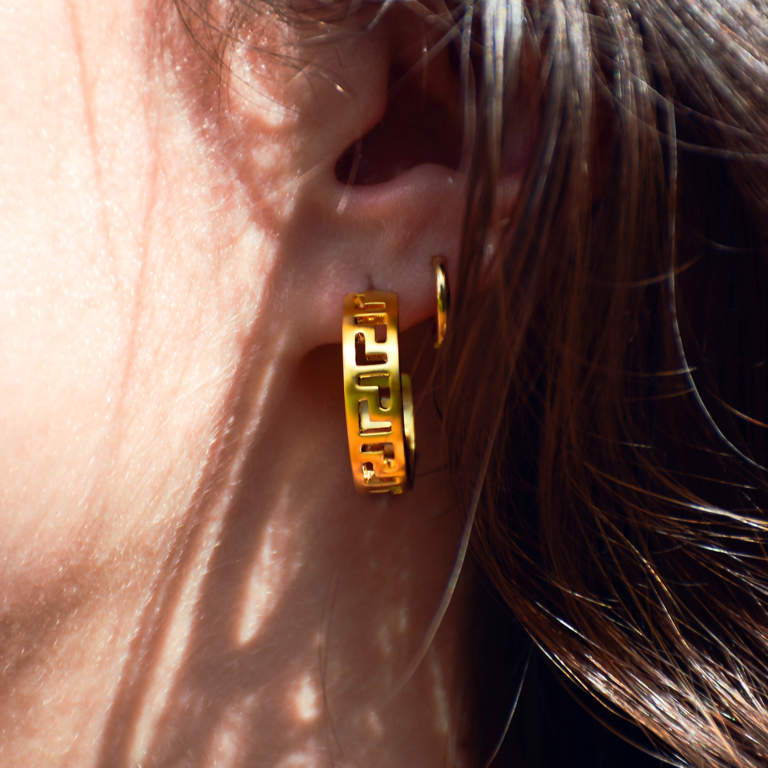 Gold earring being worn on ear.