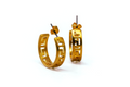 A pair of gold thick hoop earrings with an engraved meander pattern. Both have butterfly backing. On white background. 
