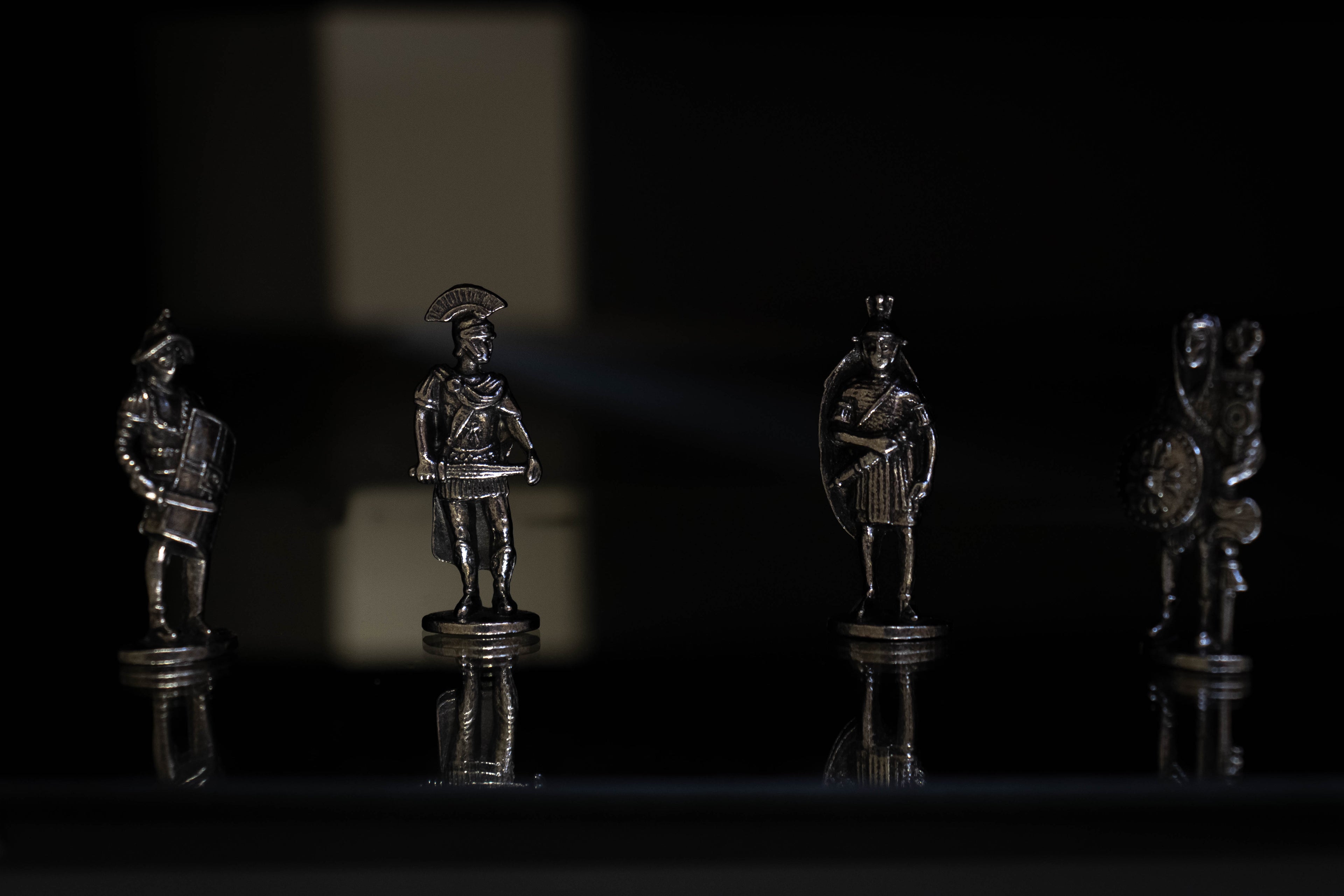 Roman military figures on creative black background with reflection underneath them. 