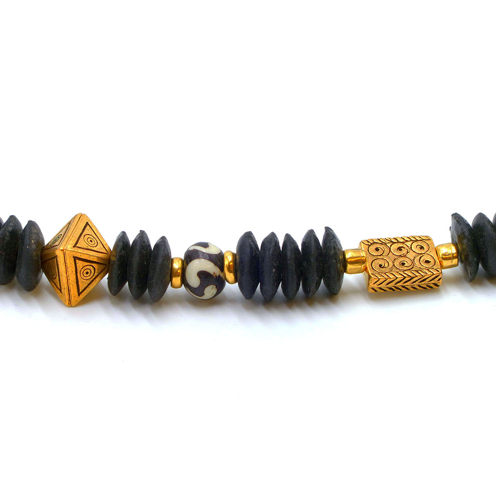 Close up of gold plated and ceramic beads of African design necklace on white background.